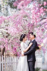 Elegant couple poses under cherry blossoms for a memorable wedding photoshoot.