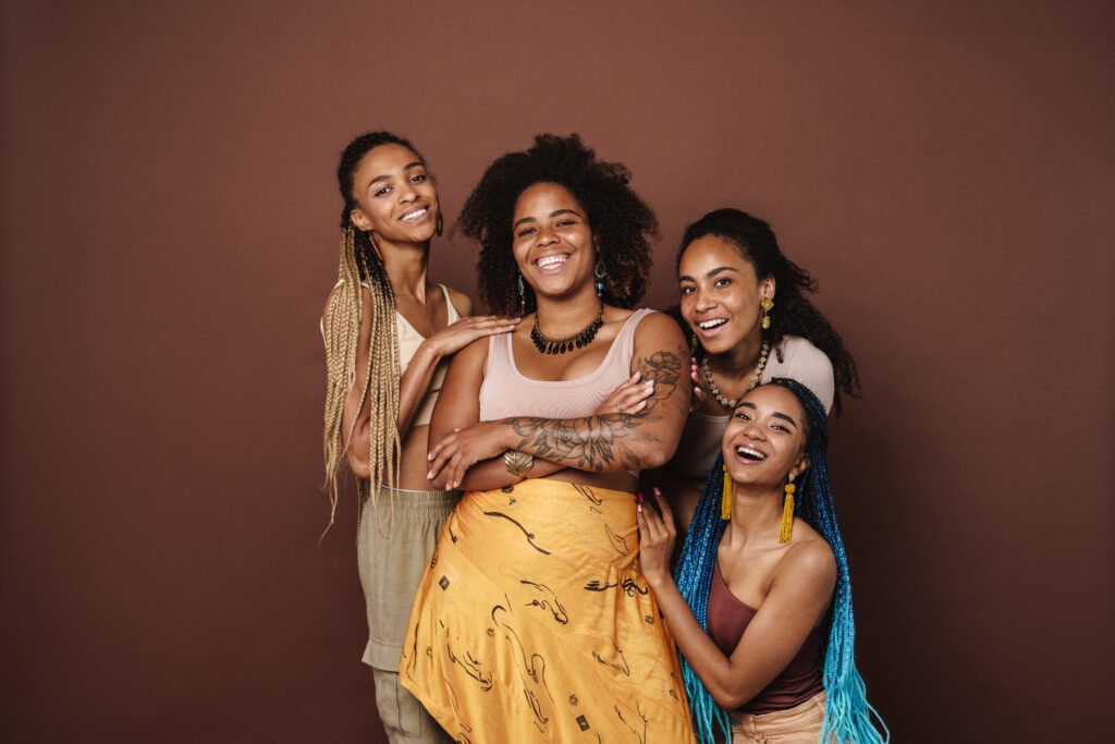 Young black four women hugging and laughing at camera